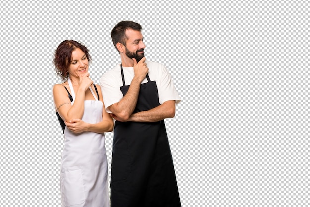 Casal de cozinheiros, olhando para o lado com a mão no queixo