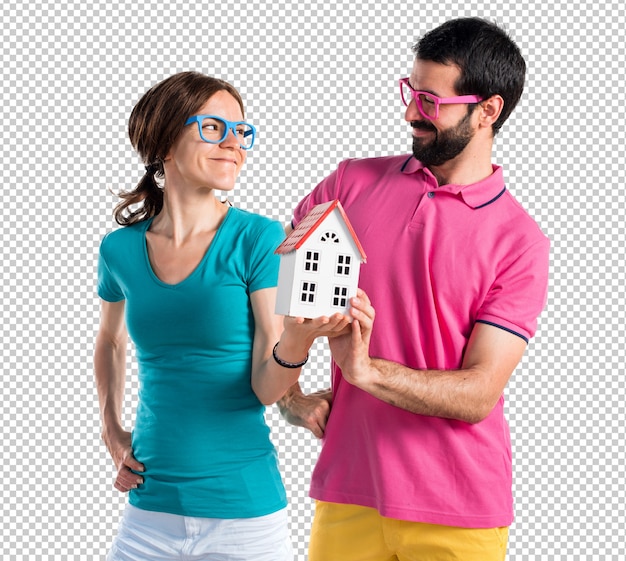 Casal em roupas coloridas, segurando uma casinha