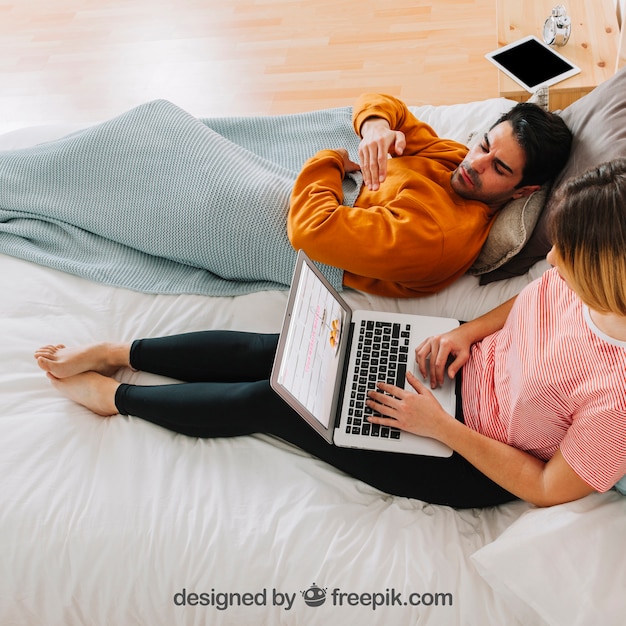 Casal moderno com laptop na cama