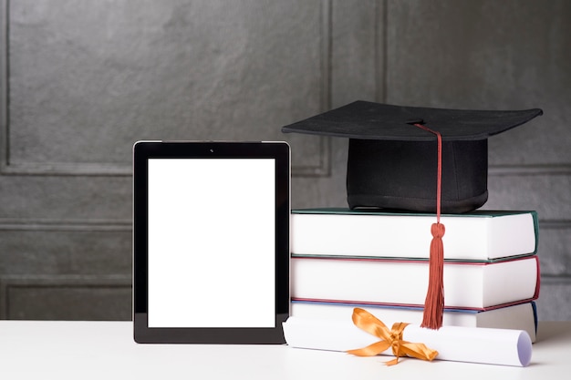 Chapéu de formatura e livros com maquete do tablet