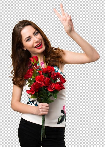 Chica joven hermosa que sostiene las flores que hacen gesto de la victoria