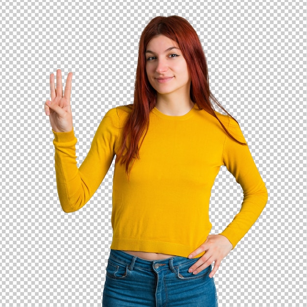 Chica joven pelirroja con suéter amarillo feliz y contando tres con los dedos