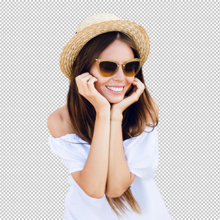 PSD chica linda con gafas de sol marrones y sombrero de paja sonríe ampliamente y sostiene sus manos cerca de la barbilla