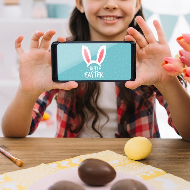 Chica con maqueta de smartphone en pascua