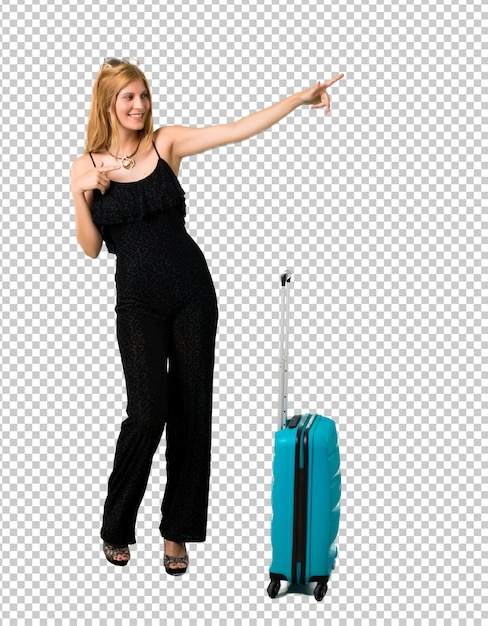 PSD chica rubia viajando con su maleta apuntando con el dedo hacia un lado y presentando un producto