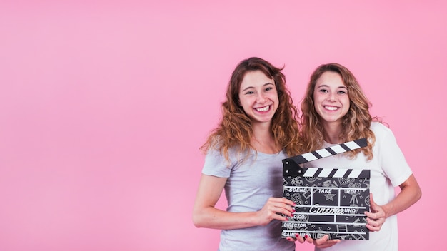 Chicas jóvenes sujetando mockup de claqueta