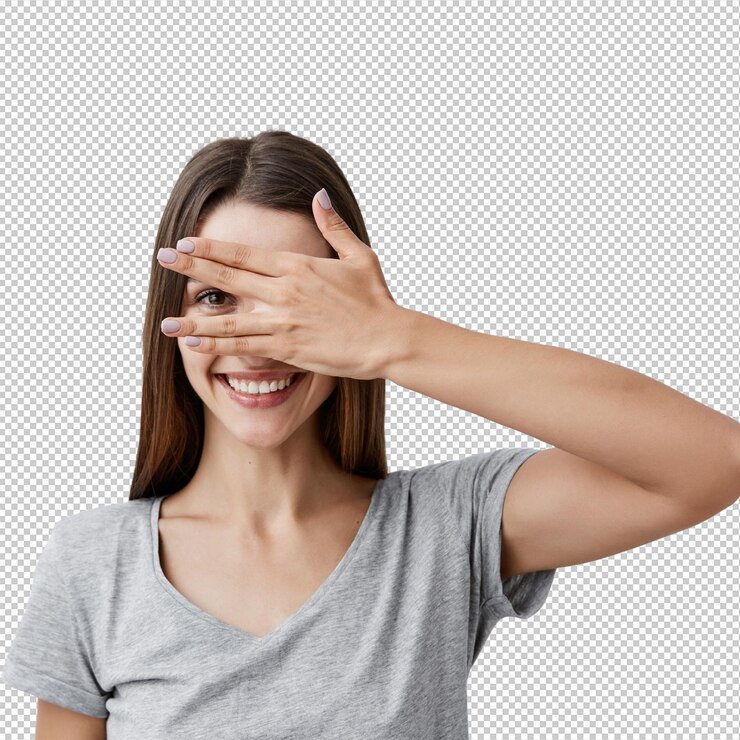 PSD close-up-porträt eines schönen, fröhlichen, jungen, kaukasischen studenten mit dunkelem, langem haar, in einem trendigen grauen t-shirt, lächelnd mit zähnen, kleidung, augen mit der hand, durch den finger mit einem auge schauend.