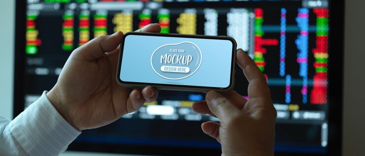PSD close up view of male office worker holding mock up horizontal smartphone at working desk
