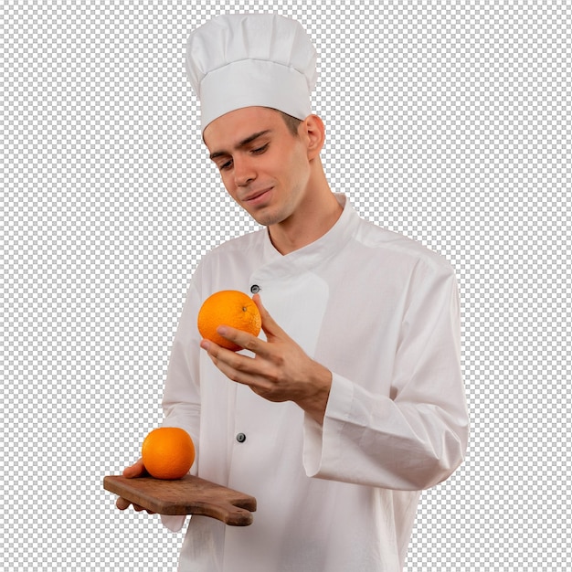 Cocinero de sexo masculino joven satisfecho con uniforme de chef sosteniendo y mirando naranja en la tabla de cortar con espacio de copia