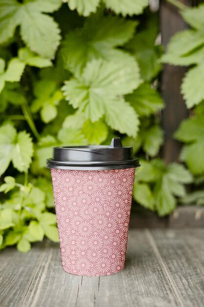Coffee Cup Mockup PSD with Pink Circle Design on Table and Green Plant Background