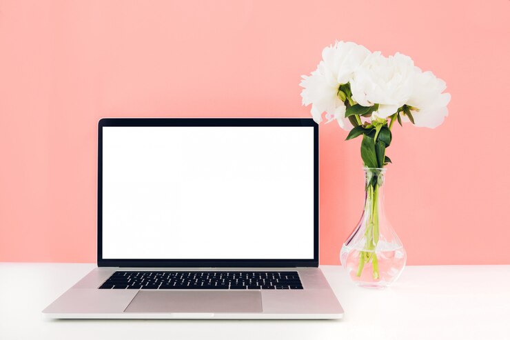 PSD computer portatile con lo schermo in bianco bianco e fiori in vaso sulla tavola