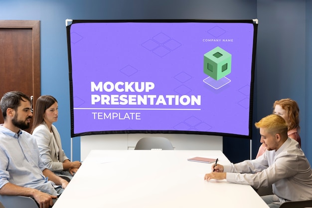 Conferencia de oficina con personas y maqueta de pantalla.
