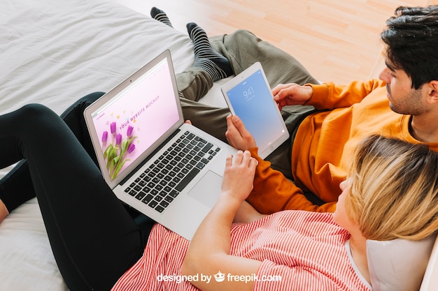 Coppia con laptop e tablet a letto