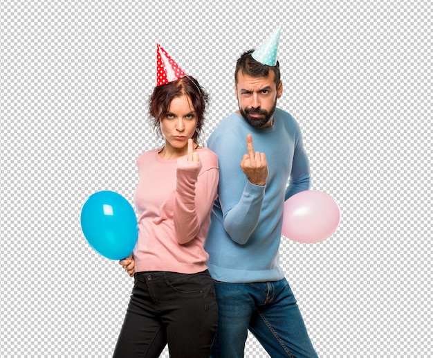 Couple Avec Des Ballons Et Des Chapeaux D'anniversaire Faisant Un Geste De Corne. Expression Négative