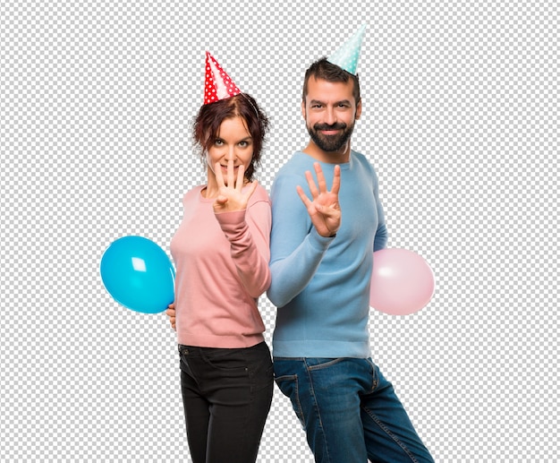 Couple Avec Des Ballons Et Des Chapeaux D'anniversaire Heureux Et Comptant Quatre Avec Les Doigts