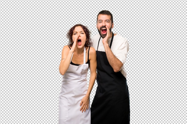 Couple De Cuisiniers Criant Avec La Bouche Grande Ouverte Et Annonçant Quelque Chose