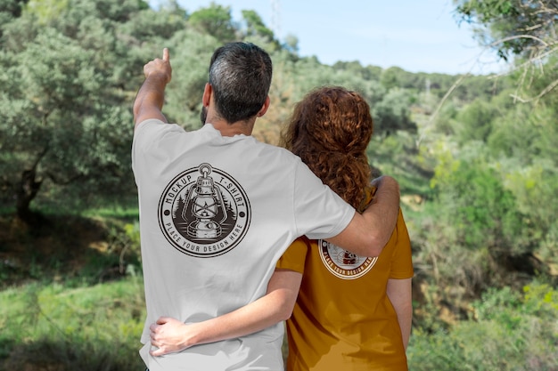 Couple à l'extérieur dans la nature portant une maquette de t-shirts