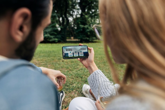 Couple regardant la maquette du smartphone dans le parc