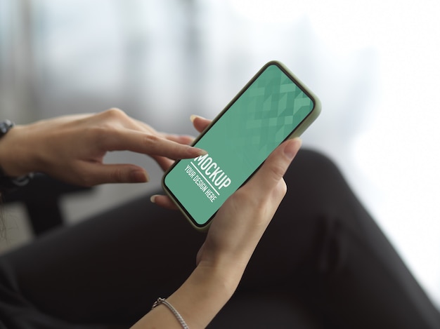 Cropped shot of female hand using smartphone include clipping path while sitting on armchair