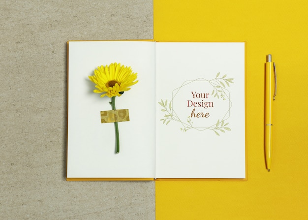 Cuaderno de la maqueta sobre fondo beige amarillo con pluma y flor de verano