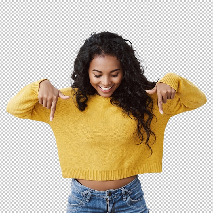 PSD curious and intrigued cute feminine african american girl in yellow sweater pointing and looking down with amused smile checking out amazing promo gazing at advertisement white wall