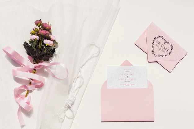 Decoración de boda en tonos rosas con invitación y flores.