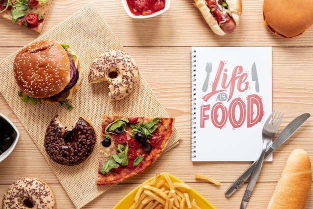 Deliciosa comida rápida en mesa de madera con maqueta de cuaderno