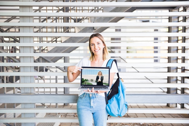 Di nuovo al concetto della scuola con la ragazza che presenta computer portatile