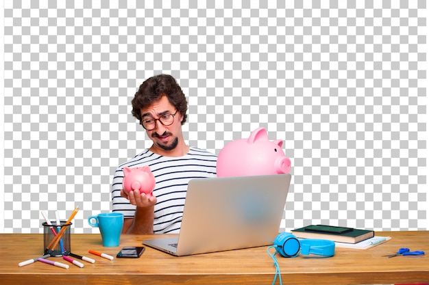 Diseñador gráfico loco joven en un escritorio con una computadora portátil y con una hucha