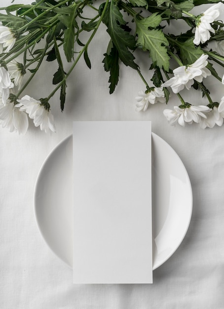 Disposição plana da mesa com maquete do menu de primavera no prato e muitas flores