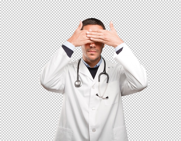 Doctor asustado que cubre sus ojos contra el fondo blanco