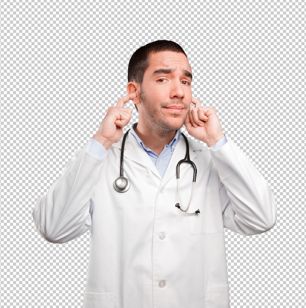 Doctor joven asustado que cubre sus oídos