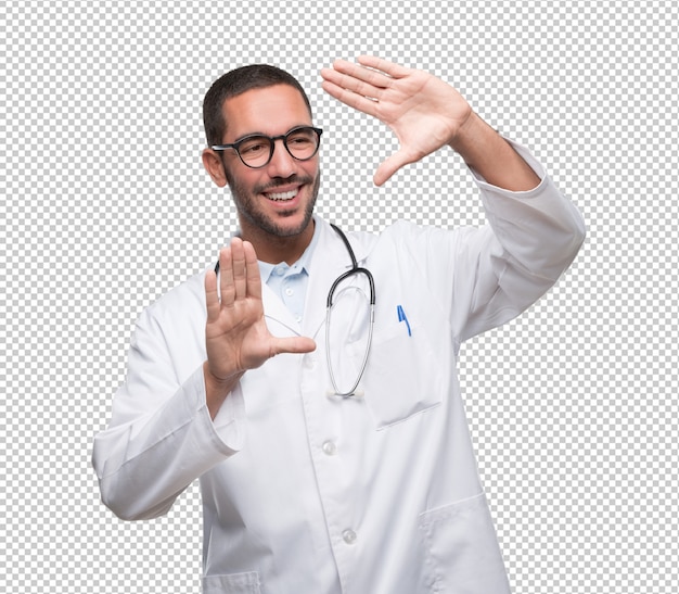 Doctor joven feliz que hace un gesto del marco con sus manos