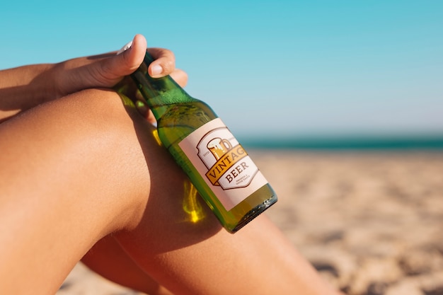 Donna con il modello di bottiglia di birra in spiaggia