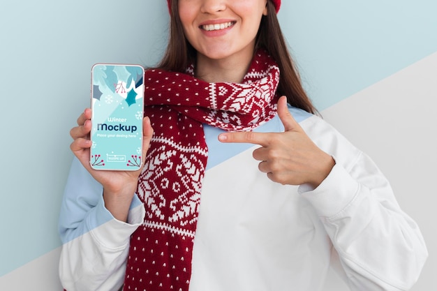 Donna felice che indossa una felpa con cappuccio e tiene in mano un modello di telefono