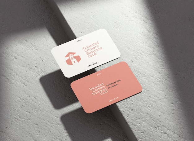 Dos maquetas de tarjetas de visita con esquinas redondeadas y sombras sobre un fondo concreto para el concepto de diseño de marca en una representación 3D realista