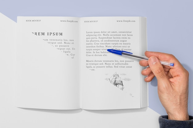 Draufsichthand, die Stift über offenem Buchmodell hält