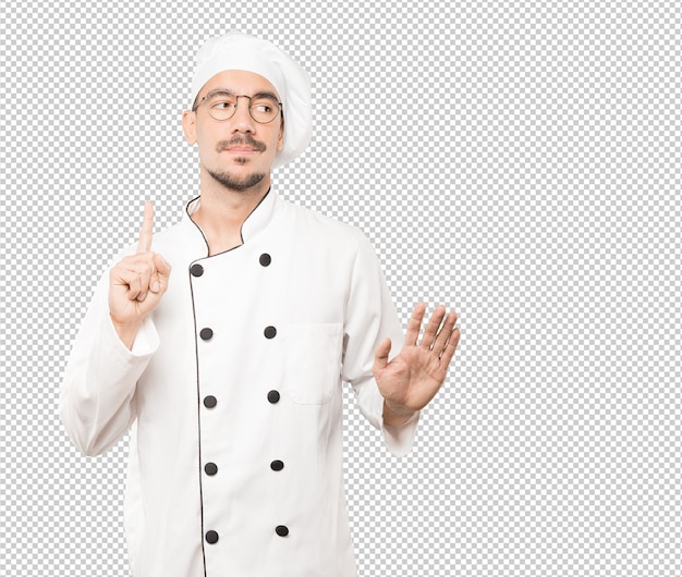 Dudoso joven chef haciendo un gesto de calma