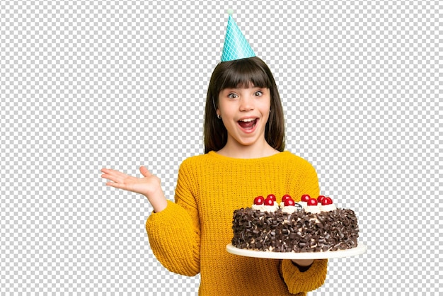 Ein kleines Mädchen hält einen Geburtstagskuchen über einem isolierten Chroma-Schlüssel-Hintergrund mit schockiertem Gesichtsausdruck
