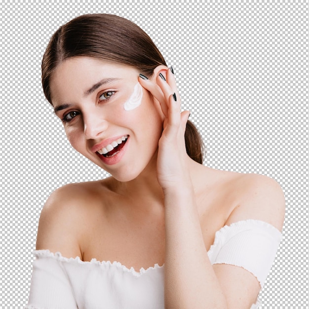 Ein lächelndes, grünes Mädchen legt Creme auf ein sauberes Gesicht, eine Brünette in einem weißen Oberteil posiert an einer isolierten Wand.