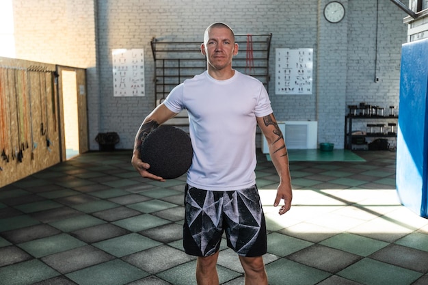 Ein Mann in einem Fitnessstudio hält einen Medizinball