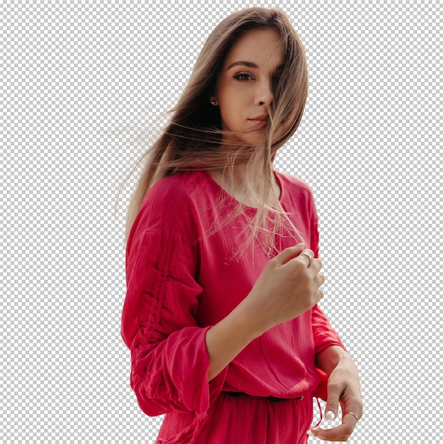 Ein stilvolles, liebenswertes weibliches Model in einem rosa Kleid posiert während eines Fotoshoot mit einem fliegenden Har auf einem verlassenen Strand