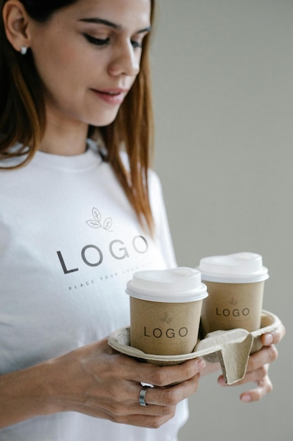 eine Frau, die Kaffeekuppen mit dem Logo des Unternehmenslogos hält