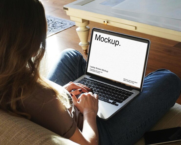 Eine Frau sitzt auf einem Sofa und benutzt einen Laptop