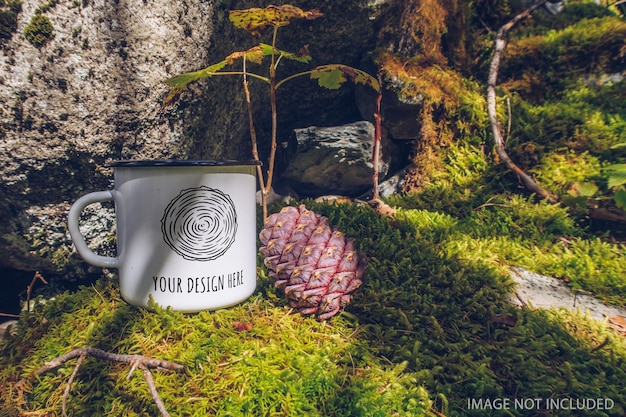 PSD emaillierter weißer becher auf dem moosigen boden mit cedar cone forest mockup trekking-waren und campingausrüstung marketing-foto stock wildwood-foto mit weißmetallbecher produktvorlage für rustikale szene