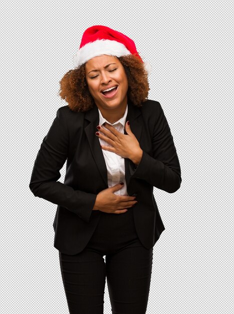 PSD empresaria negra joven que lleva un sombrero de santa de la navidad que ríe y que se divierte