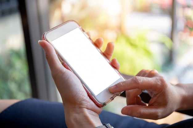 Enfoque selectivo de la mano de las mujeres utilizando teléfono inteligente móvil fondo borroso