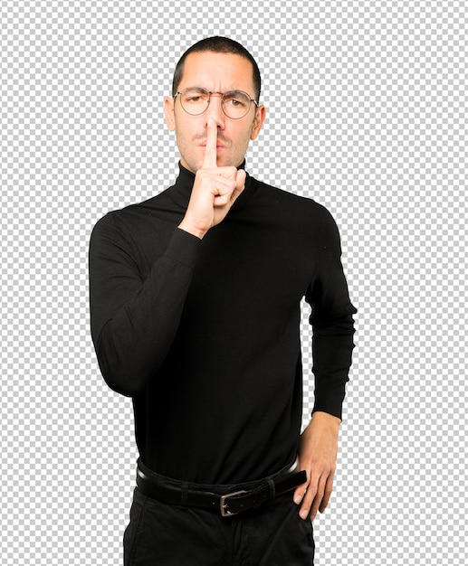 Ernsthafter junger Mann, der um Stille bittet und mit seinem Finger gestikuliert