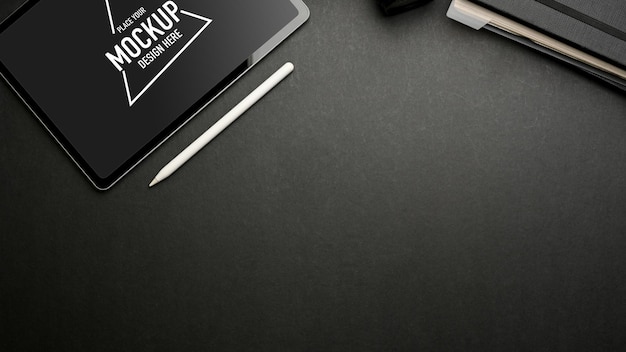 Espaço de trabalho plano criativo escuro com maquete de tablet digital na mesa escura