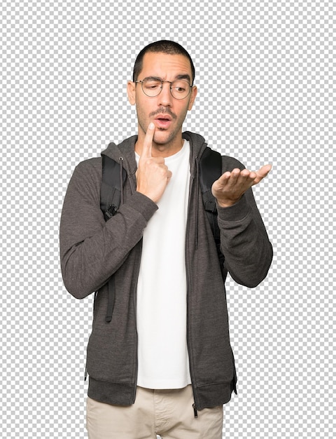 Estudiante dudoso sosteniendo algo con su mano